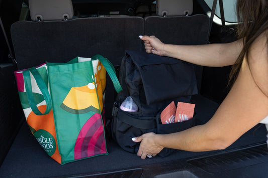Packing diaper bag with baby essentials and Milk Mom packets in car trunk