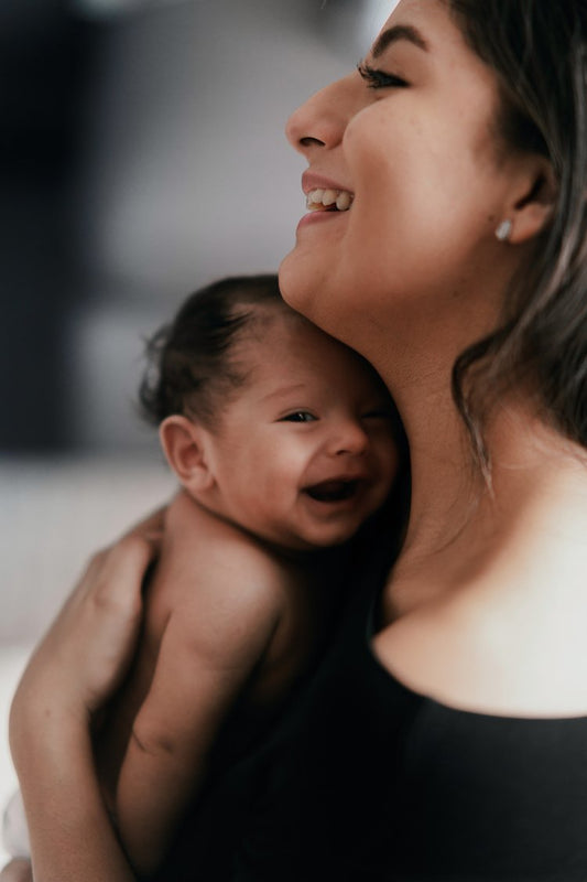 Mother smiling while holding her happy baby close to her shoulder.
