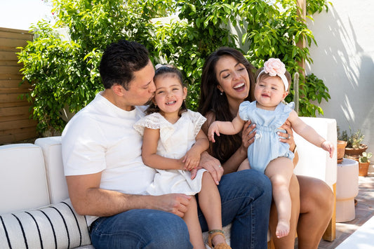 Happy family sitting outside with two young daughters