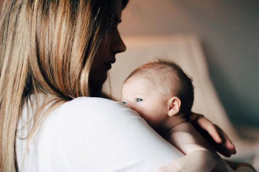 Mother holding newborn baby close in soft light