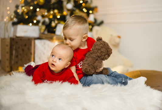 a toddler and baby boy under a christmas tree
