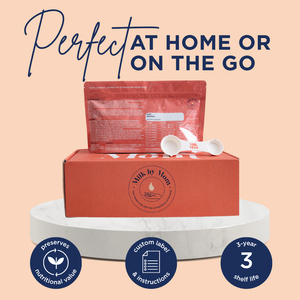 Milk by Mom powdered breast milk package and a two in one scoop displayed on top of a branded shipping box, set on a round marble stand. Text above reads 'Perfect at home or on the go.' Icons below highlight benefits: preserves nutritional value, custom label and instructions, and 3-year shelf life.