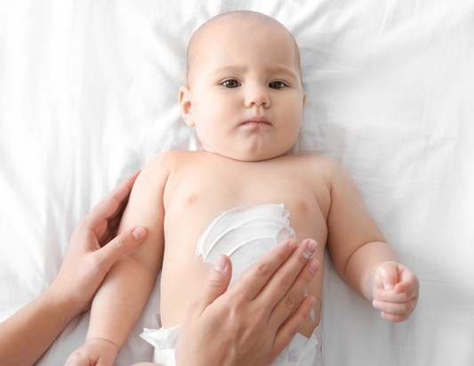 Mom's hands putting lotion on baby