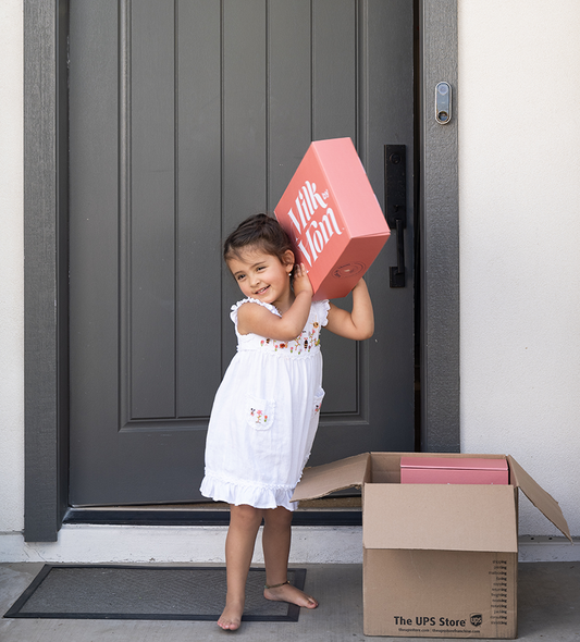 A young girl holding a shipping box of freeze-dried breast milk with the Milk by Mom logo