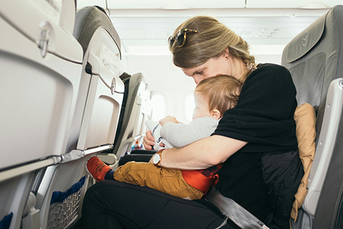 A mom holding her baby on an airplane