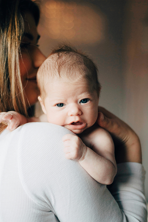 a newborn baby looking over his mom's shoulder