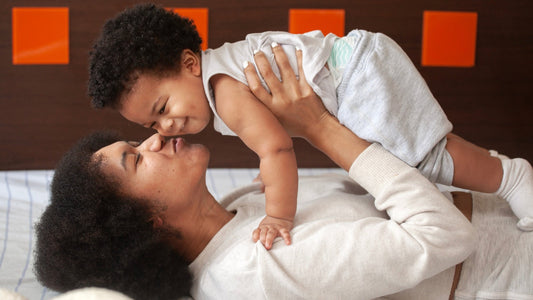Mother breastfeeding baby while kissing baby's hand