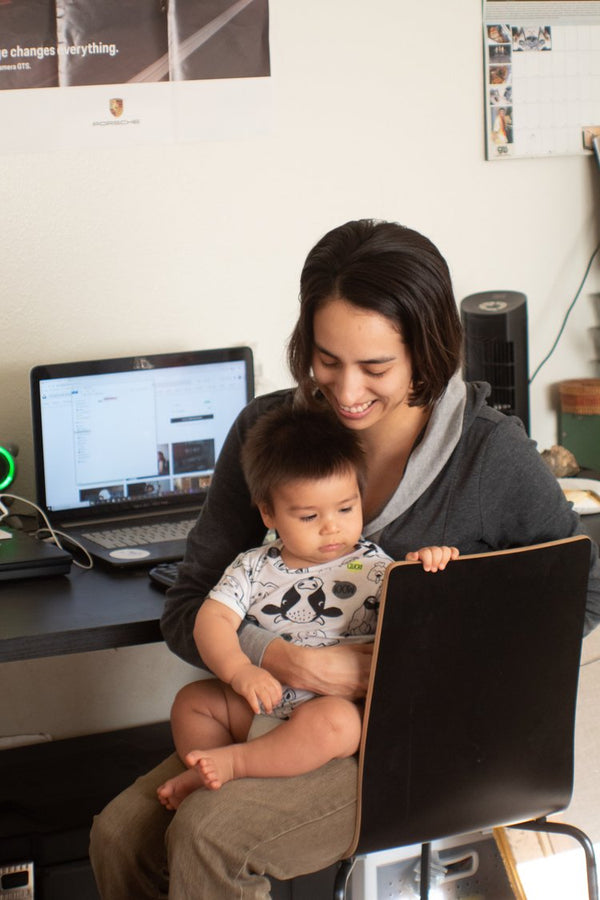 Mother working at desk with baby on lap.
