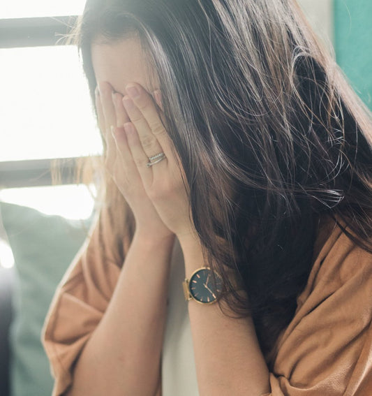 Stressed woman covering face with hands at home