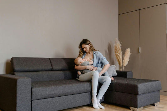 Mother breastfeeding baby on couch at home, comfortable nursing and bonding moment