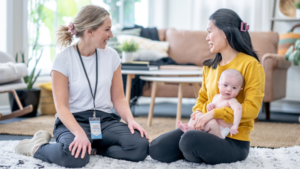 Lactation consultant supporting mom and baby during breastfeeding support session at home