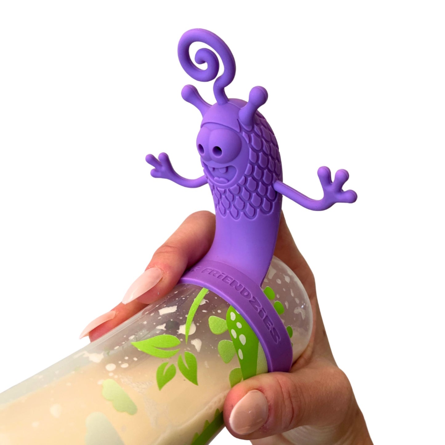 Hand holding a baby bottle filled with milk and topped with a purple silicone bottle toy attachment designed to keep babies entertained and focused during feeding