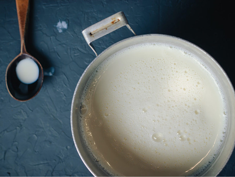 Top view of milk in a pot with a spoon, representing milk preparation, warming, and everyday feeding routines for babies and families