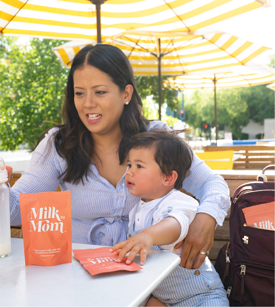 Mom and toddler sitting at an outdoor café with Milk by Mom freeze-dried breast milk pouches, highlighting on-the-go feeding, travel-friendly breast milk storage, and convenient nutrition for busy families