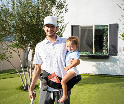 Dad holding his toddler outdoors with a Milk by Mom freeze-dried breast milk pouch in a carrier, highlighting convenient, on-the-go breast milk nutrition for active families
