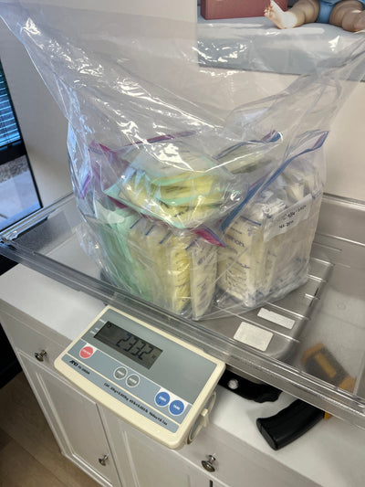 Frozen breast milk storage bags grouped inside a clear protective bag while being weighed on a digital scale