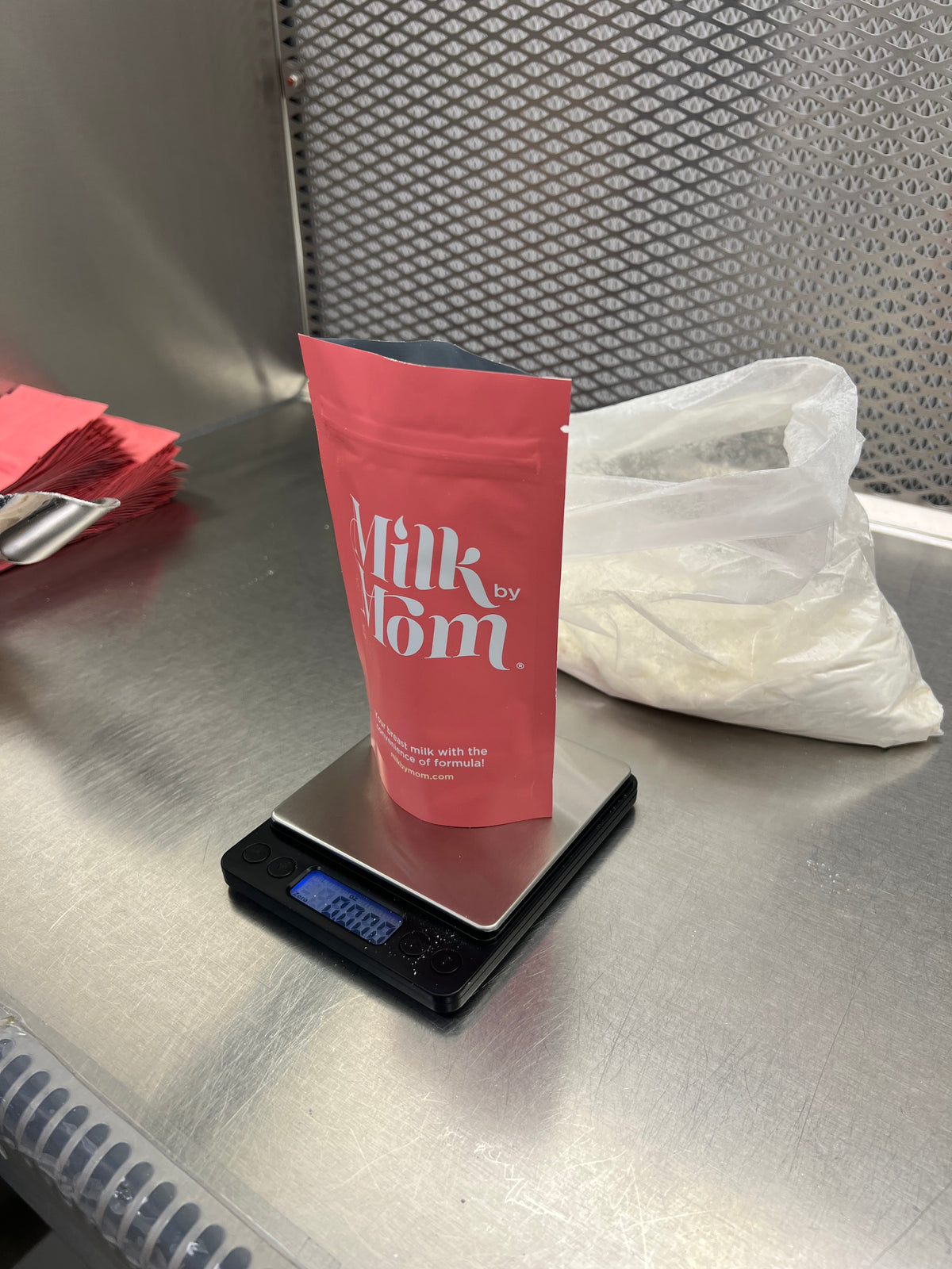 Milk by Mom freeze-dried breast milk pouch being weighed on a digital scale in a stainless-steel processing area