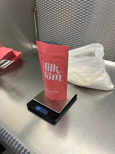 Milk by Mom freeze-dried breast milk pouch being weighed on a digital scale in a stainless-steel processing area