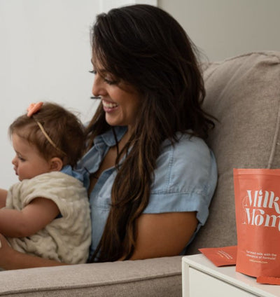 Mom and baby bonding during story time beside Milk by Mom breast milk powder and prepared bottle on nursery table