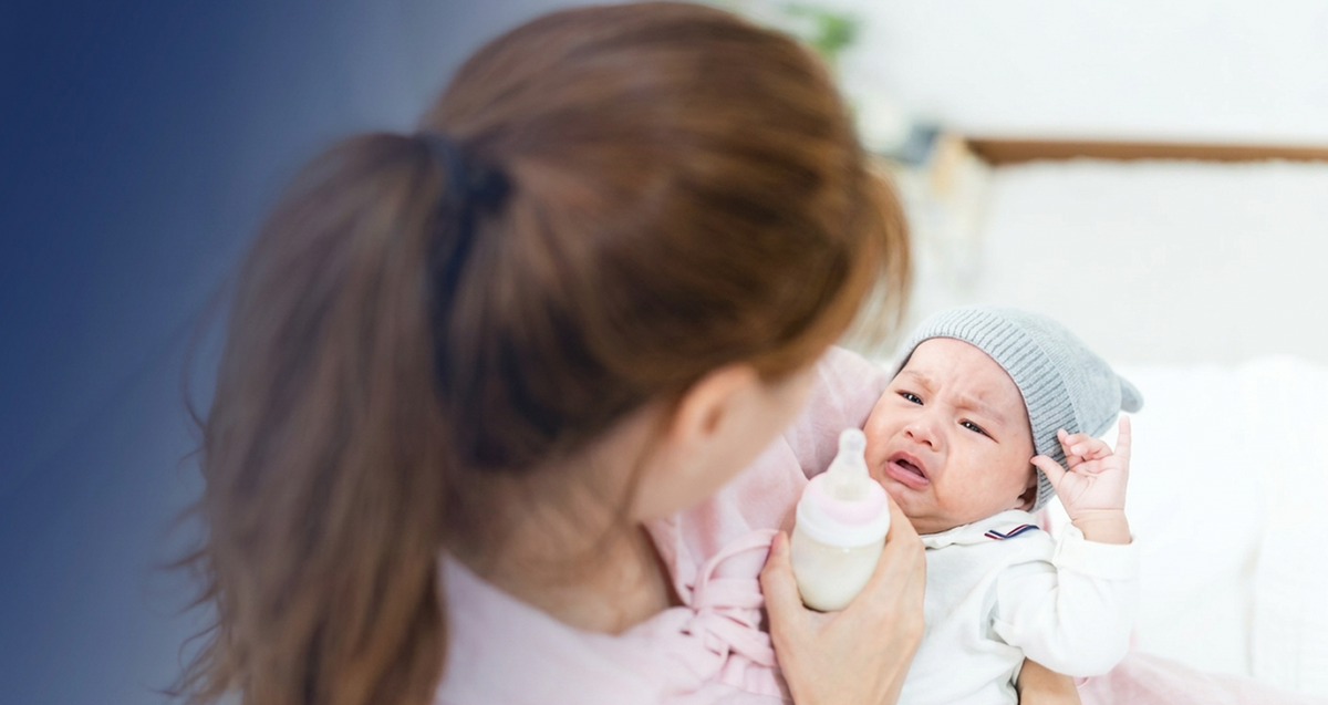 Mother feeding a crying newborn with a bottle, highlighting real-life infant feeding challenges, soothing techniques, and everyday parenting moments