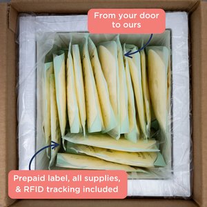 Insulated shipping box filled with sealed breast milk storage bags, neatly packed upright. Overlaid text reads 'From your door to ours' and 'Prepaid label, all supplies, & RFID tracking included,' emphasizing the service’s shipping convenience.